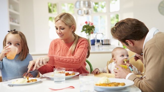 Family With Young Baby Eating Meal At Home