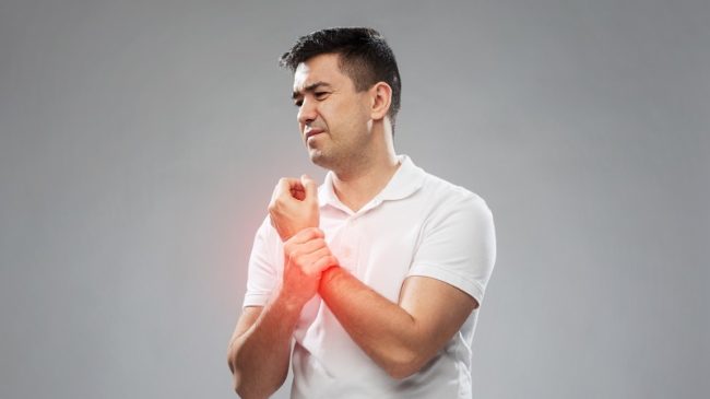 unhappy man suffering from pain in hand