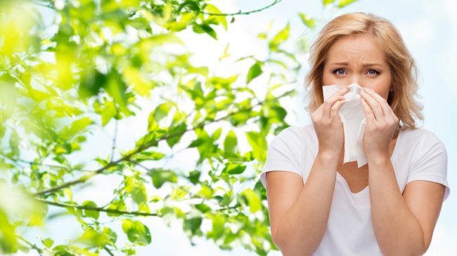 unhappy woman with paper napkin blowing nose