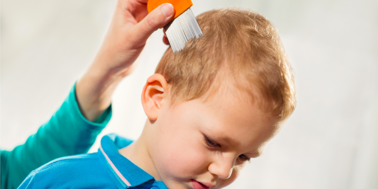 Ein Erwachsener kämmt vorsichtig die Haare eines kleinen Jungen mit einem orangefarbenen Kamm.