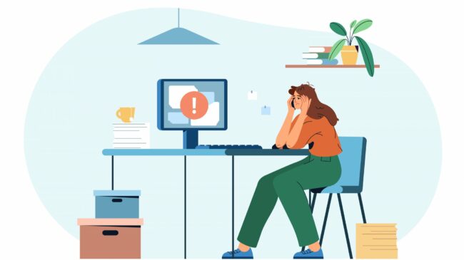 Eine gestresste Frau sitzt an einem Schreibtisch mit einem Computer, der eine Fehlermeldung anzeigt, umgeben von Unterlagen und Pflanzen.