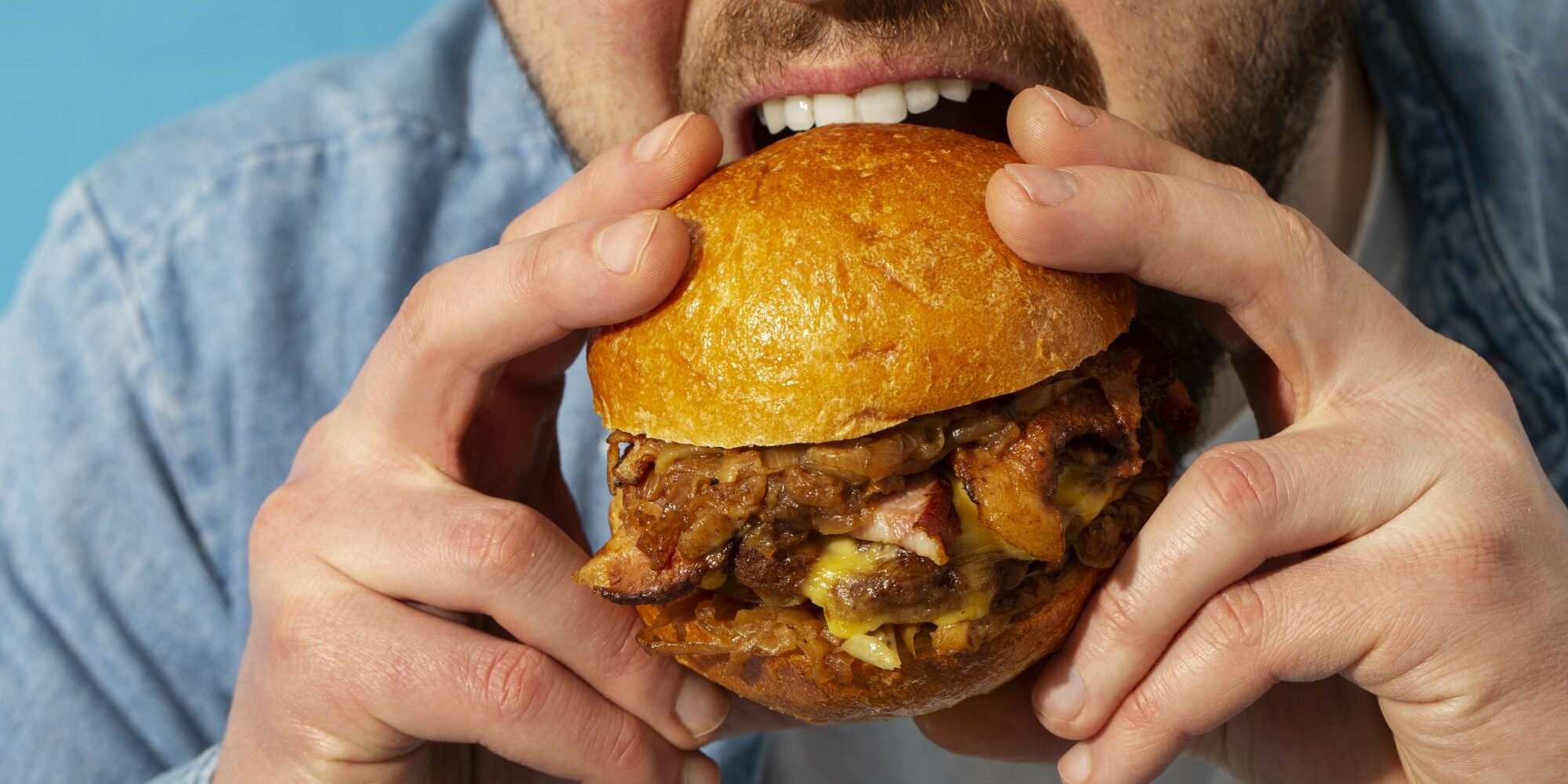 Eine Person hält einen saftigen Burger mit einem goldenen Brötchen und beabsichtigt, ihn zu essen.