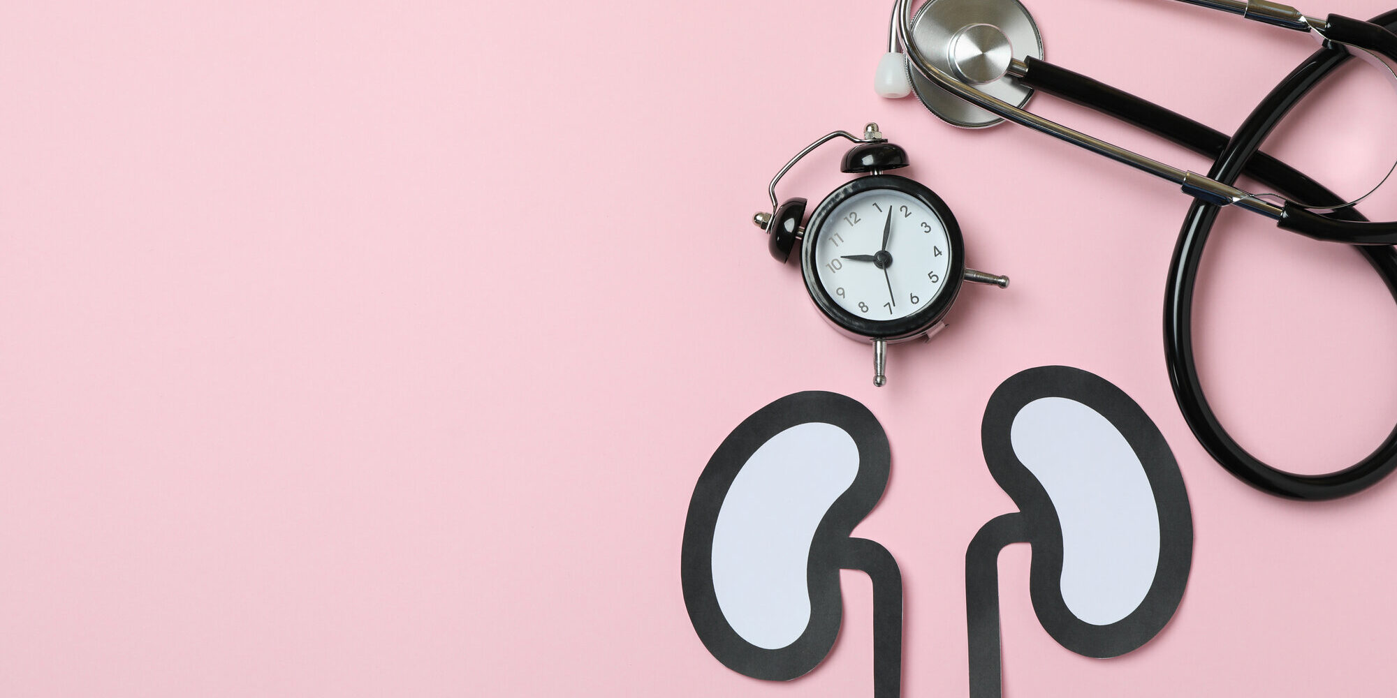 nieren-gesundheit.jpg Papierfiguren von Nieren auf einem rosa Hintergrund, daneben eine Armbanduhr und ein Stethoskop.
